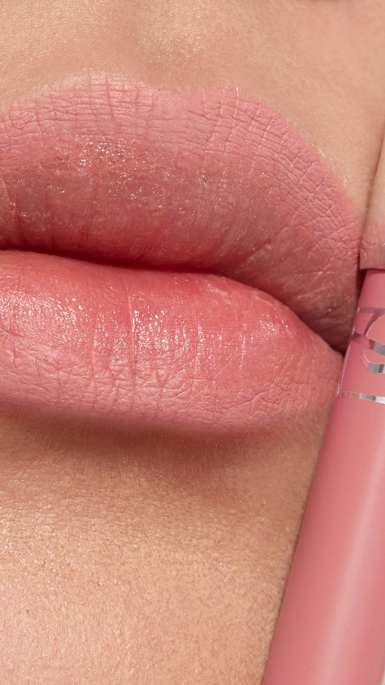Vertical close-up of lips with soft pink matte lipstick and a matching product tube.