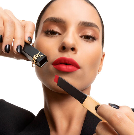Hand presenting a YSL square lipstick in soft pink beside the cheek.