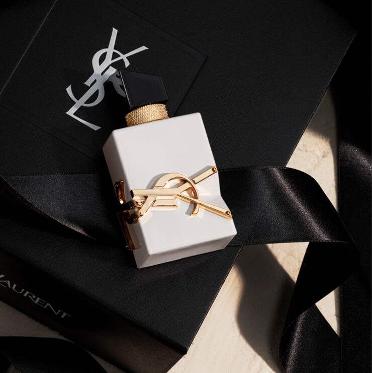 A sleek, opaque white bottle of Libre resting on a black YSL gift box with a silk ribbon.