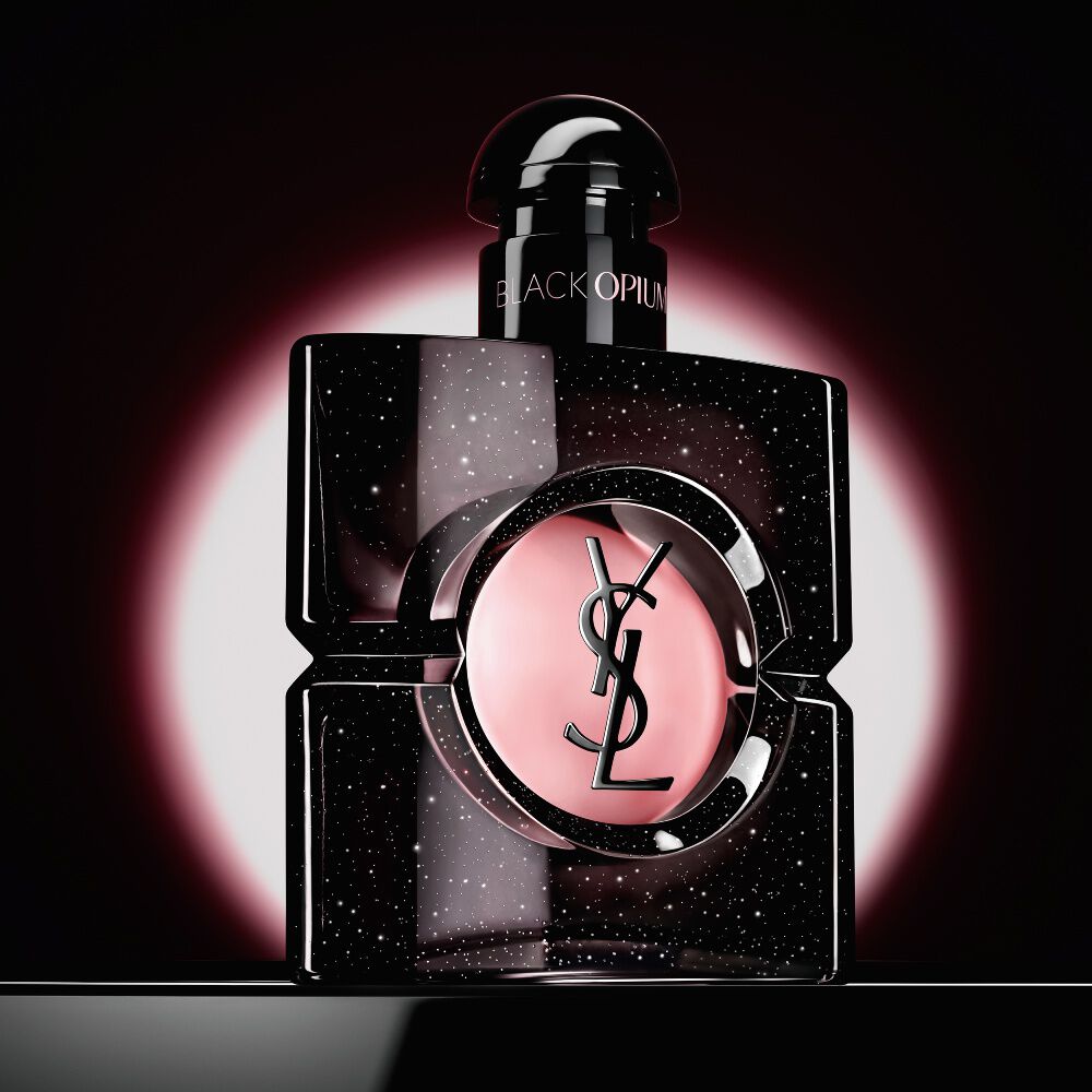 Black Opium Eau de Parfum bottle highlighted by a pink circular glow on a dark background.