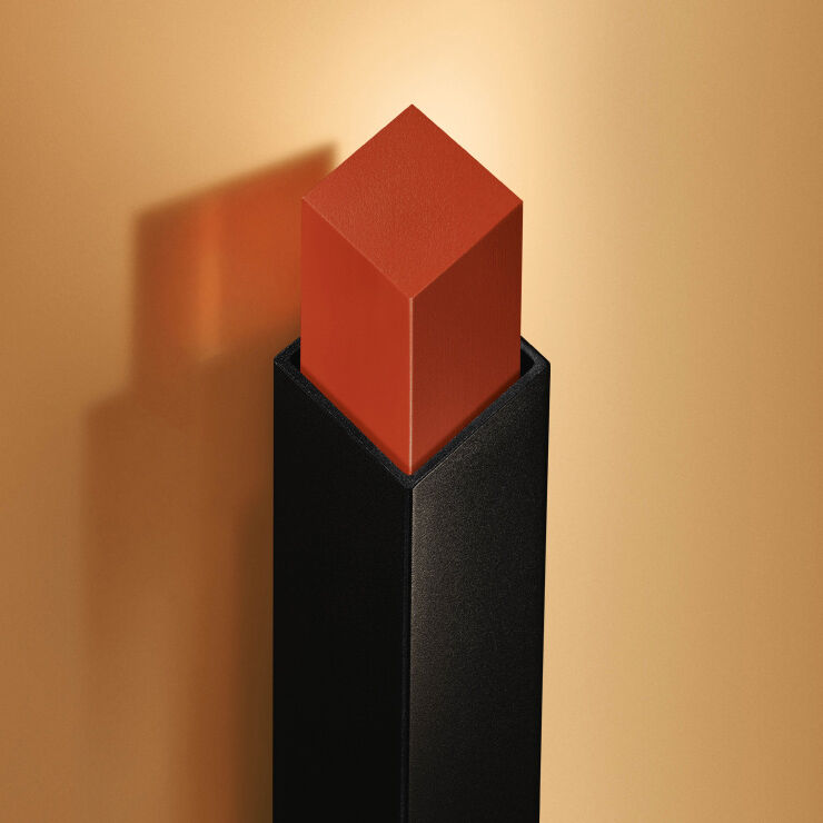 Close-up of coral lips applying a square lipstick bullet.